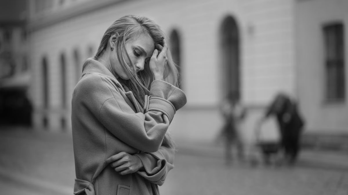 Thoughtful woman in an urban setting, reflecting in black and white photography.